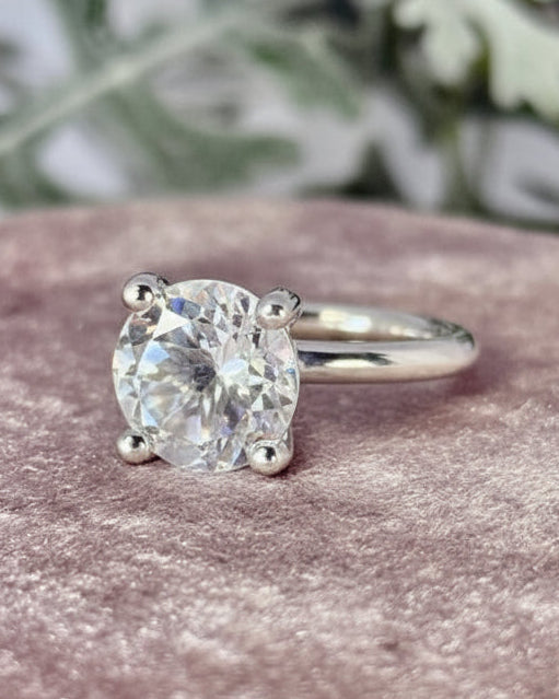Ring i silver med vit berkgristall på rosa underlag